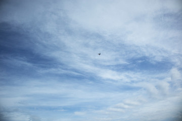Fototapeta na wymiar Clear blue sky, clouds and airplane silhouette, horizontal orientation