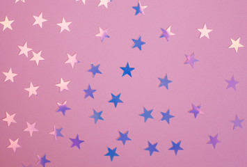 Pink and purple shiny star confetti over pink background.