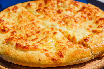 Four cheese pizza quattro fromaggi on a wooden board, blue background