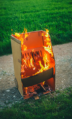 Fake cardboard grill is burning hard. Cardboard grill made out of fun or for a party caught fire and is burning in the open air.