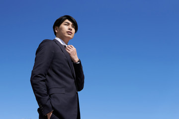 青空背景の日本人男性ビジネスマン