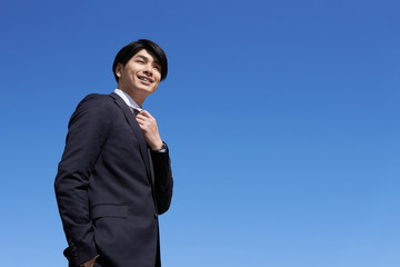 青空背景の日本人男性ビジネスマン