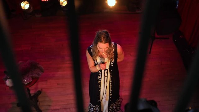 High-angle balcony view of young confident female role model giving speech on empowering woman in society at a small authentic venue