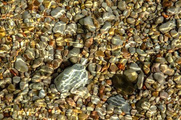 Pebbles under sea water on the sea beach.