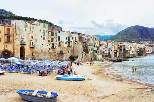 Seaside with boats and people on beach in Cefalu Sicily