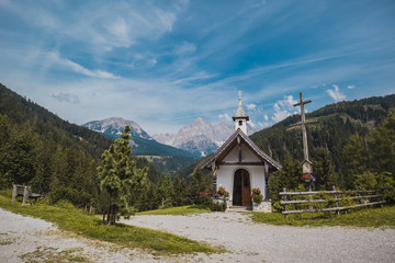 Fototapeta na wymiar Beautiful Mandlberg kapelle or chapel in the austrian Tauern alps close to Mandling in front of breathtaking view of Dachstein glacier on a hot summer day.