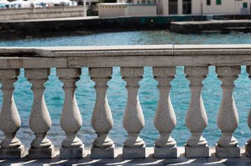Antique-like stone fence with colums at the waterfront street near the sea