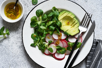 Corn salad with avocado and radish with mustard and honey sauce. Vitamin salad, top view.