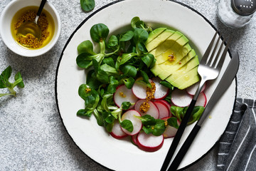 Corn salad with avocado and radish with mustard and honey sauce. Vitamin salad, top view.