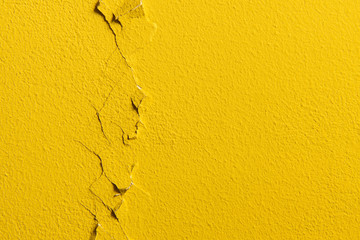 Vertical crack on a yellow painted wall