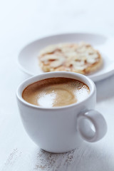 Cup of coffee and almond cookies on white background. Close up.
