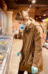Obraz premium girl in a protective mask and gloves against coronavirus in a supermarket. beautiful young woman. grocery store. Russian girl. Covid-2019.
