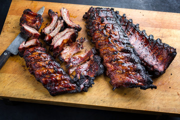 Barbecue pork spare loin ribs St Louis cut with hot honey chili marinade sliced and burnt as closeup on a wooden cutting board