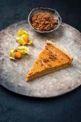 Traditional French Tarte au citron piece with orange and physalis fruit offered as closeup on a modern design plate