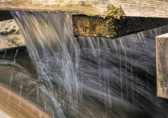 Wasser fließt an einem Brett im Bach herunter Langzeitaufnahme