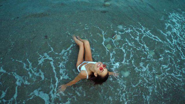 top view Pretty slim girl in bikini having fun beach vacation resort rolling wawes pebble beach