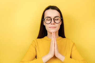 Calm young woman practicing yoga, breathing, mindful young female meditating with closed eyes,...
