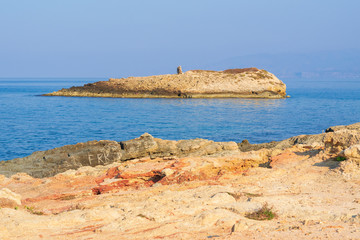 Fototapeta na wymiar lonely island near Crete beach in sunset time. Greece vacation. symbol of loneliness, copy space.