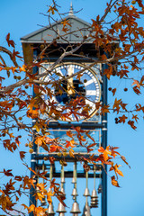 Clock tower clock face with fall leaves and blue sky background
