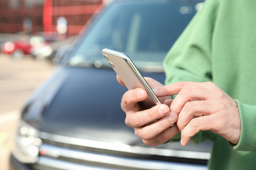 Man ordering taxi with smartphone on city street, closeup