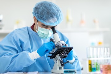 Asian scientists wear protective clothing looking for microscopes while doing medical research in a science laboratory.