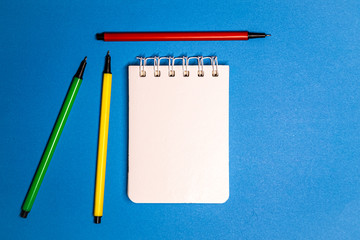 Notebook with a To Do list. Flat lay style picture of workspace with office supplies on a blue background. Top view