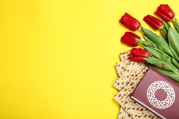 Tasty matzos, Torah and flowers on yellow background, flat lay with space for text. Passover (Pesach) Seder