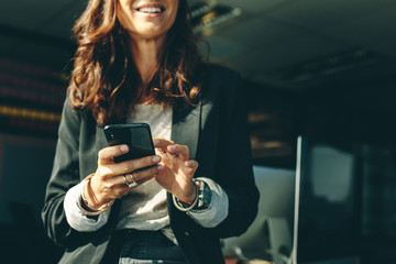 Businesswoman with a on mobile phone in office - obrazy, fototapety, plakaty