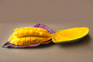 Mango cut into slices on a leaf on a beige background