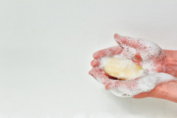 Soapy foam hands holding soap bar. Washing hands. Photo on white background with copy blank space.