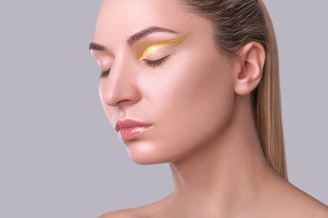 Portrait of a beautiful happy woman with beautiful creative makeup in gold colors. Make-up concept.
