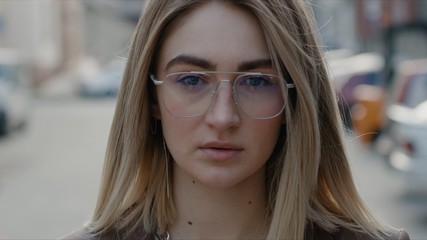Fototapeta na wymiar Extrime close up view of gorgeous stylish blonde caucasian young woman in glasses looks to the camera hair blows in the wind sunny day successful female business spring portrait beauty outdoor