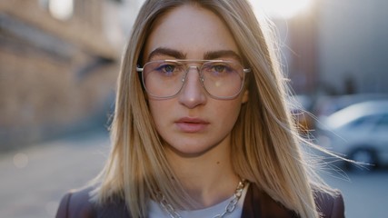 Close up portrait of attractive dreaming european blonde hair woman in glasses looks to the camera spring sunny day sunlight outdoor beauty business sun girl female