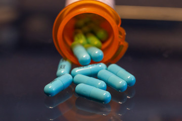 blue pills spilled out on table with bottle