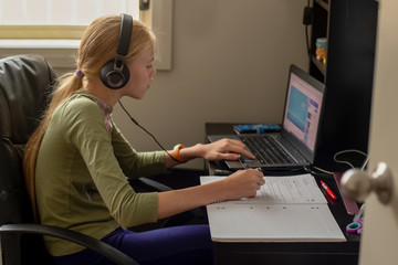 Fototapeta na wymiar Stay home: Teenage girl sitting with laptop, notebook and tablet - online learning from home. Self isolation coronavirus concept