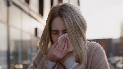 Close up young european woman stand sneezing coughs feel sick fever flu coronavirus symptoms cold allergy city beautiful disease female nose lady runny tissue air pollution adult illness district