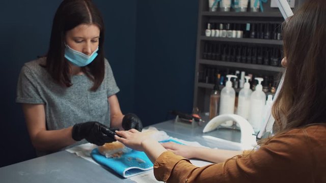 Spa Salon. Manicure. Paraffin Hand Bath. process paraffin treatment. Bowl, additive. Wax bathtub Care. Nail care. Nail artist doing manicure. Professional master putting mitten on hand customer