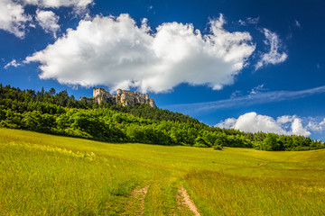 The ruins of a medieval castle Lietava on a rocky blade over a wooded landscape and grassy meadows, nearby Zilina town, Slovakia, Europe.