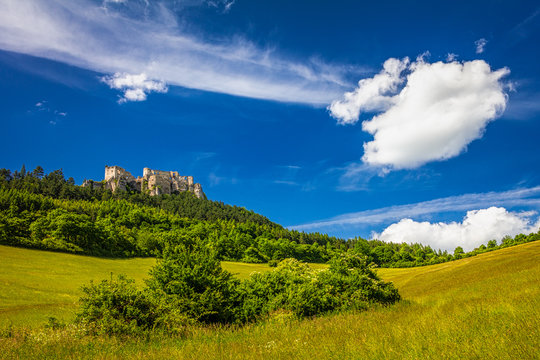 The ruins of a medieval castle Lietava on a rocky blade over a wooded landscape and grassy meadows, nearby Zilina town, Slovakia, Europe.