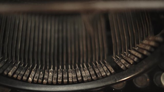 Slow motion typewriter strikers typing. Vintage typewriter, pan right to left, slow motion camera truck right to left. Gritty industrial machine. News type, gritty crime drama