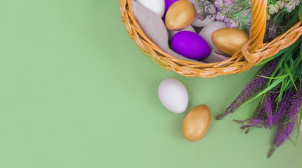 Happy Easter Day.Greeting card or banner for sale of a store or website.Golden, white, purple eggs in a basket on a green background next to a bouquet of greenery.Provence.Copy space.Top view