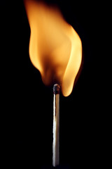 A burning safety match with black background
