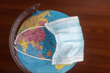 The concept of the globe is covered with a protective mask against coronavirus covid 19 infection.