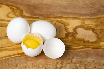 White chicken eggs and broken eggs on wooden board or table. close up