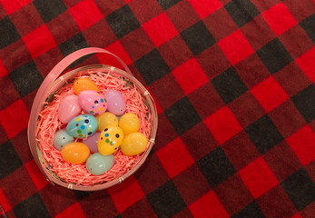 Easter Egg bunny basket sitting on a red plaid blanket filled with colorful eggs