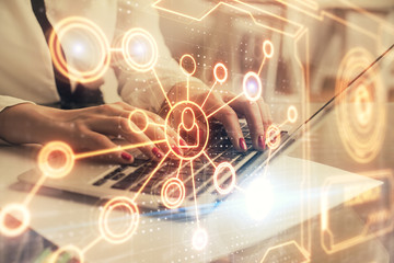 Double exposure of woman hands typing on computer and social network theme hologram drawing. People...