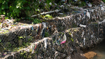 River bank with plastic garbage. It cannot be recycled and pollutes the environment