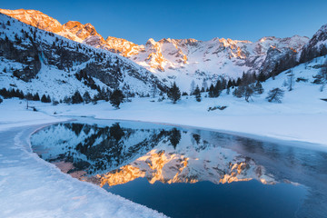Frozen lake Aviolo at sunset, Adamello park, Italy.