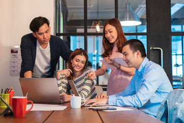 Asian young startup team in casual uniform discussing and working together in modern co-working space office. startup, casual work, communication, lifestyle, brainstorming or young business concept