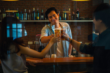 Group of Asian friend clinking a glass of beer and enjoy drinking beer at bar, alcohol, beer drinking, friend party, group of friend, casual meeting, bar and restaurant or friend and beer concept